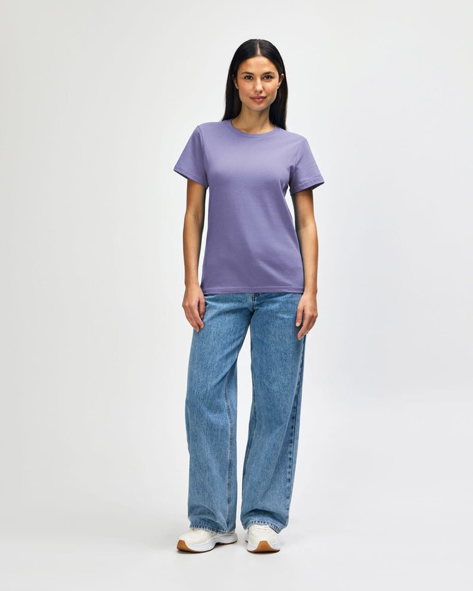 A purple midweight t-shirt is worn with blue jeans and white shoes, featuring a logo on the shirt.