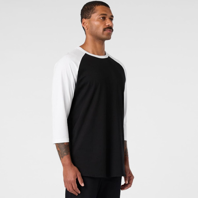 A black and white raglan tee featuring three-quarter sleeves, displayed on a model against a plain background.