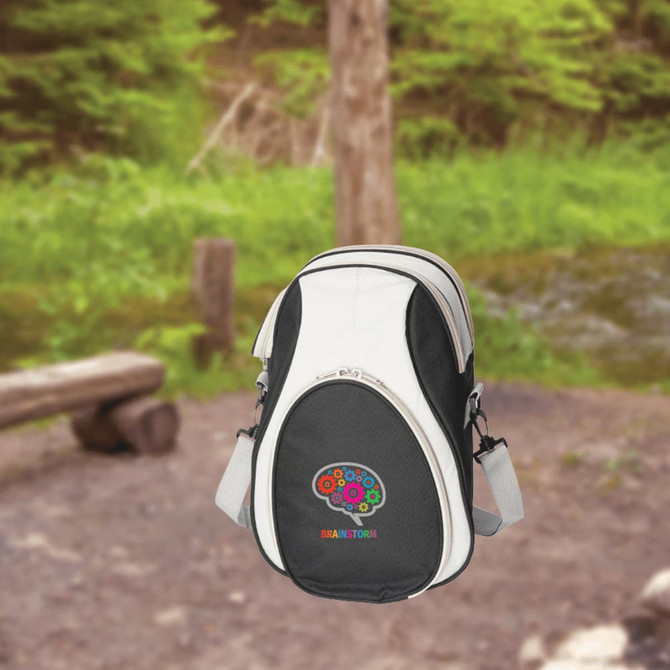 A black and white cooler bag with a logo, set against a natural outdoor background.