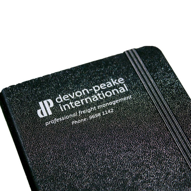 A black bound journal with a textured cover, featuring a logo and branding on the front.