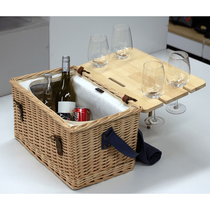 A wicker picnic basket in natural tones, featuring a bamboo table and glasses, with wine and drinks inside.