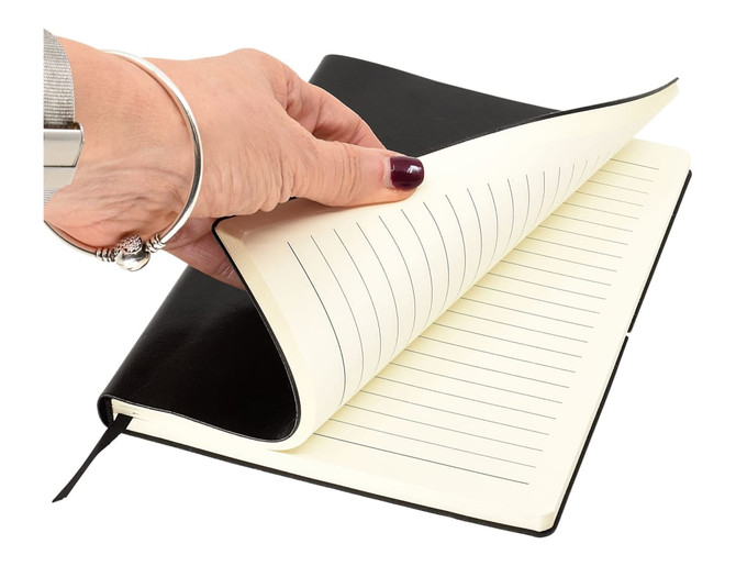 A hand holding a black Tango A5 notebook, revealing lined pages inside. The notebook features a ribbon bookmark.