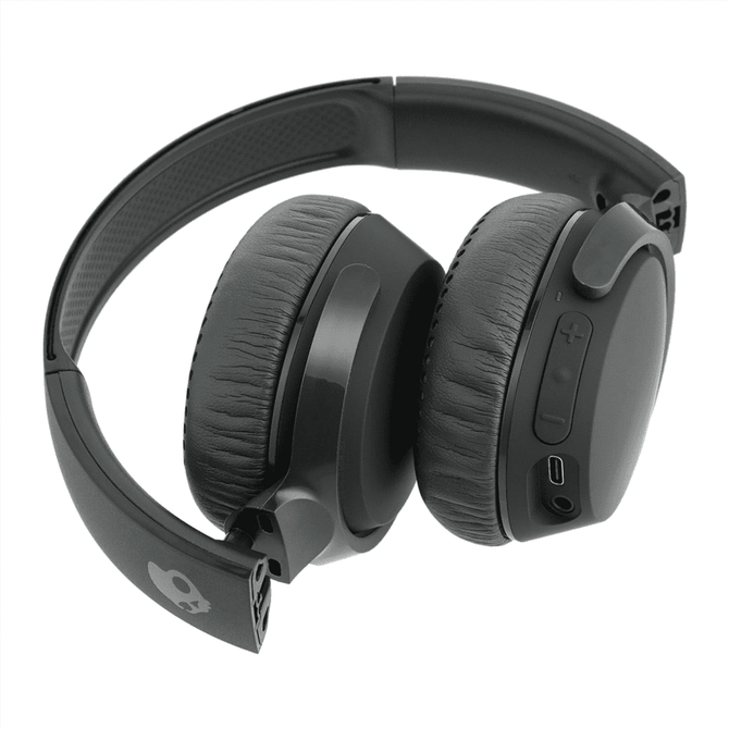 A pair of black wireless headphones with cushioned ear pads and a logo on the side. The headphones feature buttons and a charging port.