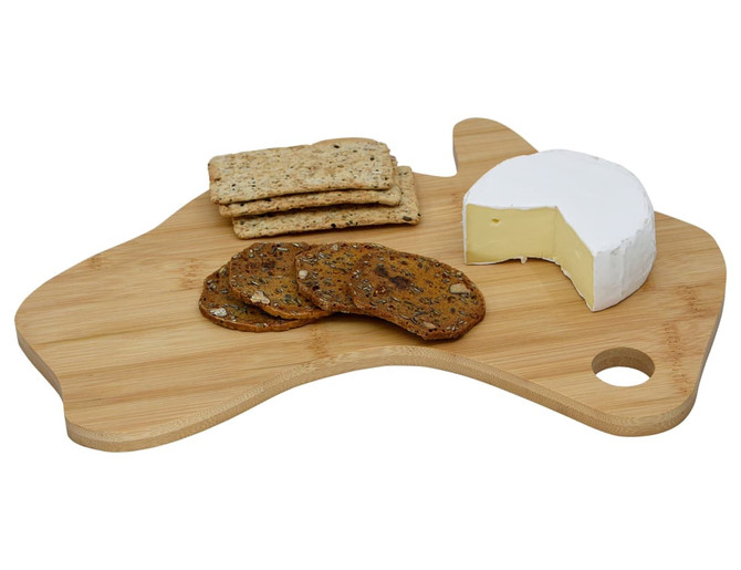 A bamboo cheese board in the shape of Australia with cheese, crackers, and cookies displayed on top.
