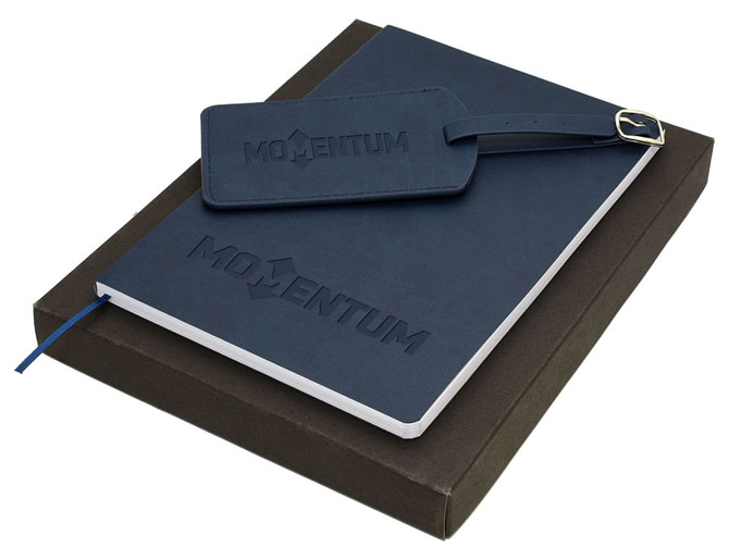 A navy travel journal set with a notebook and a matching luggage tag, presented in a dark box.