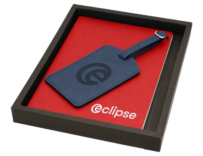 A red journal and a blue luggage tag in a black box, featuring a logo on the tag and journal cover.