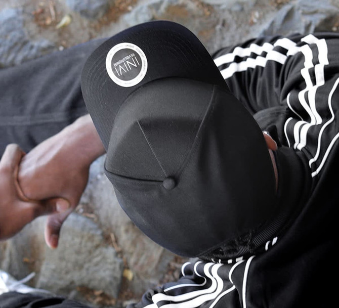 A black cap with a logo, featuring a sleek design, resting on a person’s head.