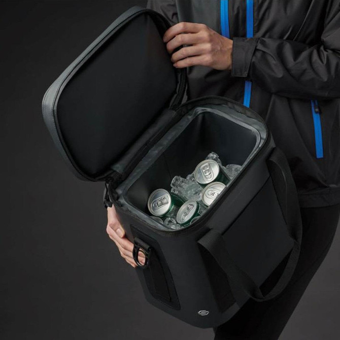 A black cooler bag with a zippered lid, filled with drink cans and ice, held by a person wearing a jacket.