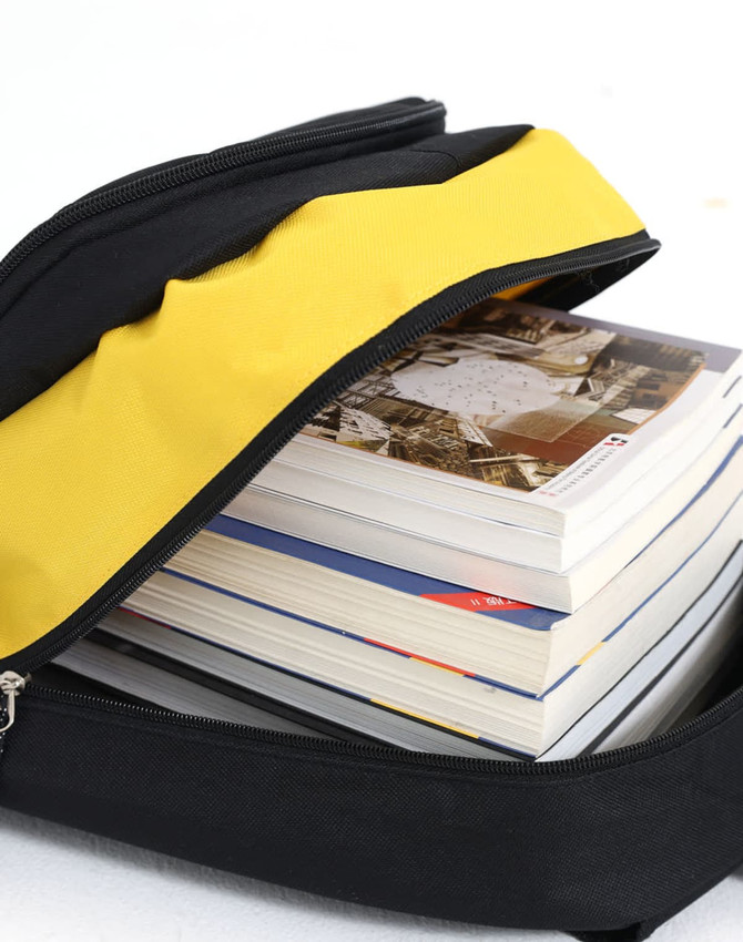 A black and yellow backpack unzipped with several stacked books visible inside. The backpack features a logo.