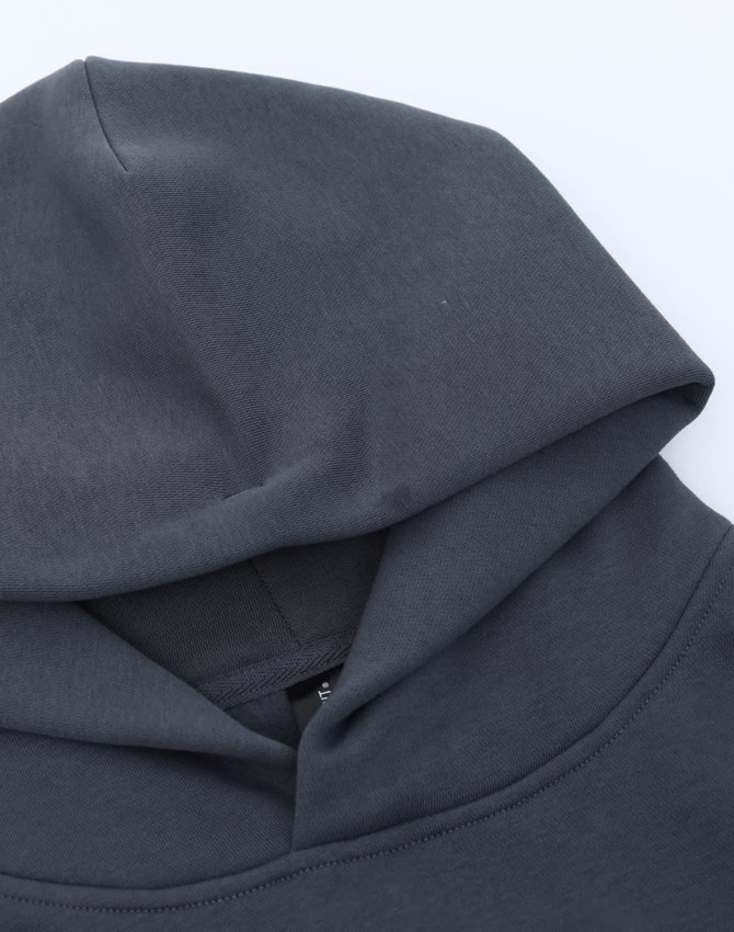 A grey unisex premium fleece oversized hoodie with a large hood, featuring a branding label.