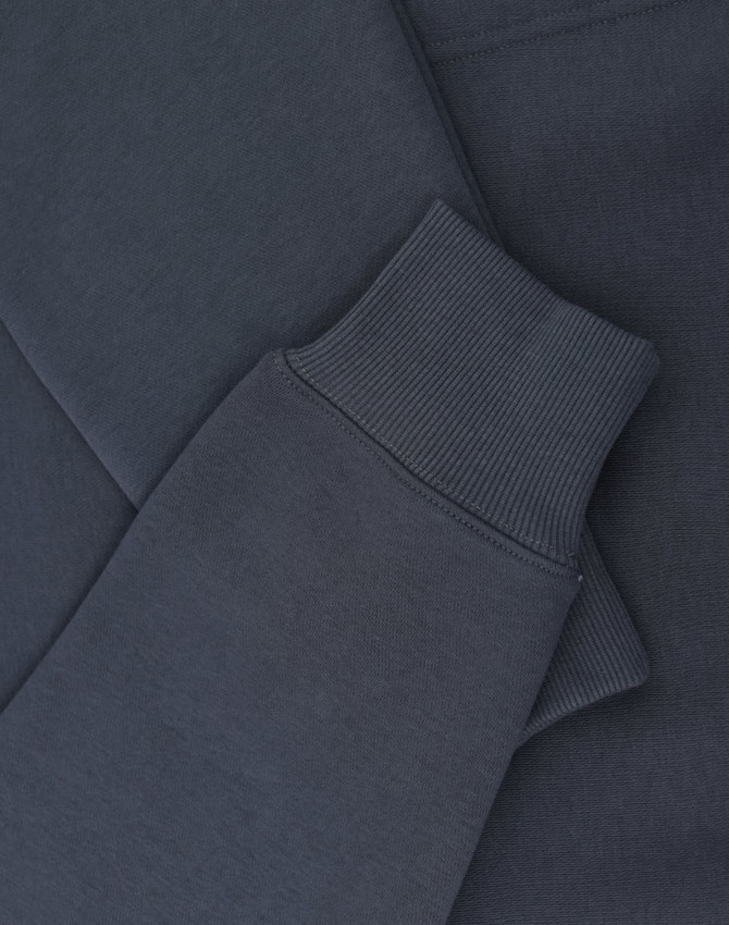 A close-up of a navy oversized hoodie featuring ribbed cuffs and soft fleece material. It includes a logo.
