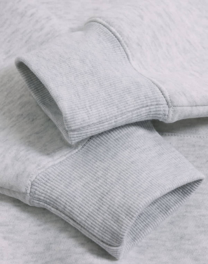 Close-up of a light grey fleece oversized hoodie featuring ribbed cuffs and a soft texture.