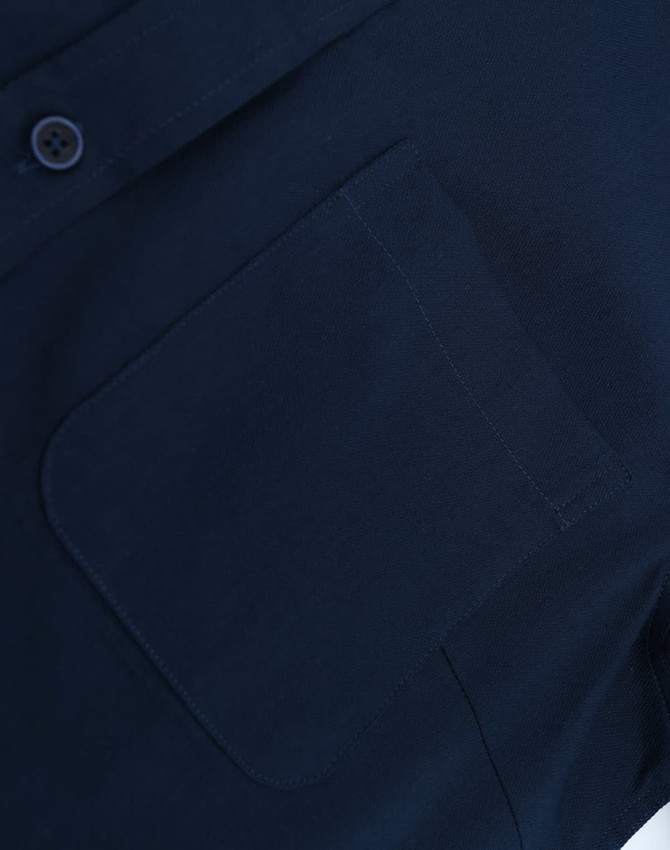 A navy blue long-sleeve shirt with a buttoned collar and a pocket on the front. Features a logo detail.