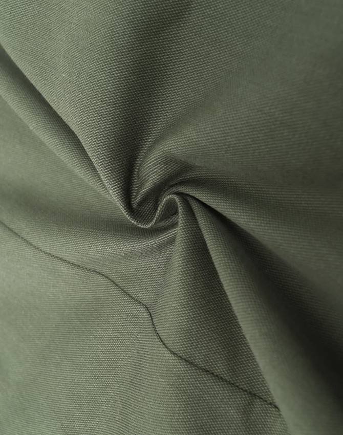 A close-up of dark green cotton blend fabric, showcasing its texture and softness. The material is smoothly folded.