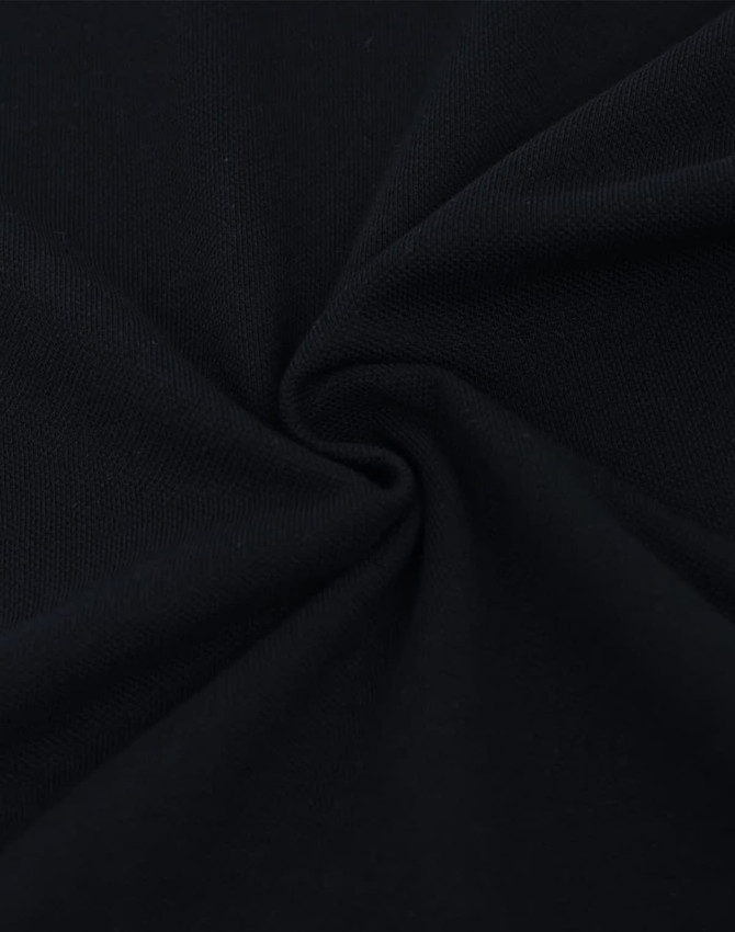 A close-up of black cotton/poly pique fabric, showing its soft texture and drape. The image has a swirling pattern.