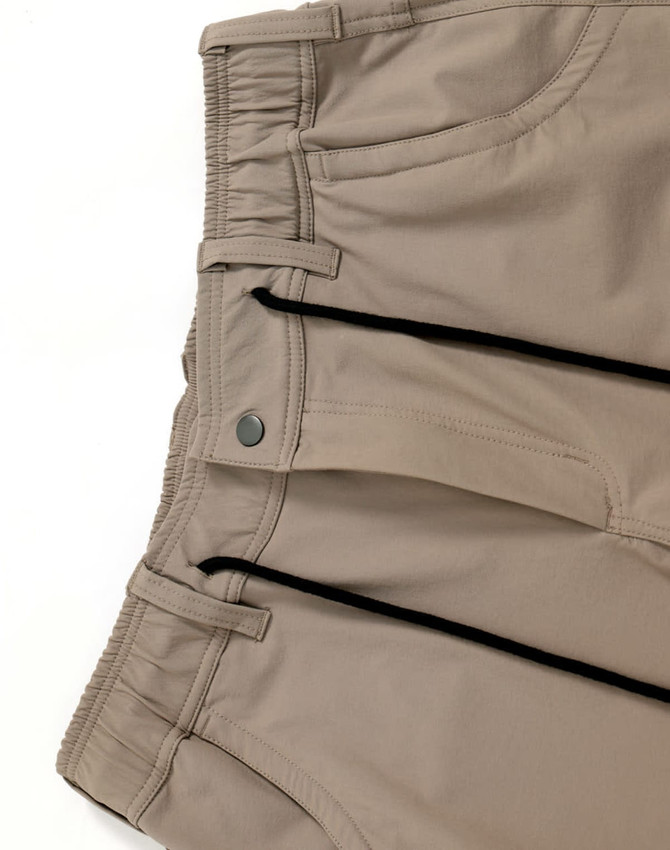 Beige water-repellent flexi work pants featuring elastic waistband and zippered pockets, with branding on the fabric.