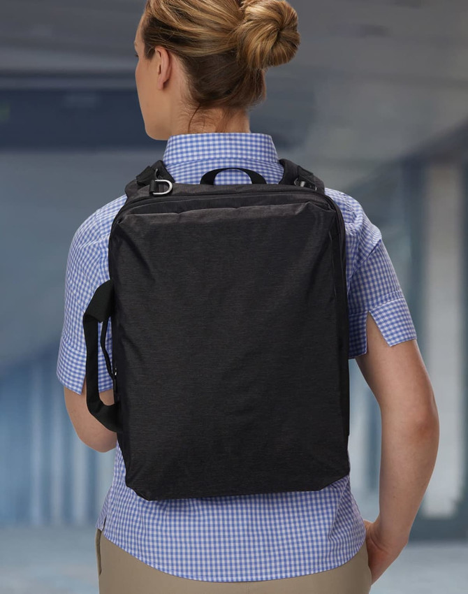 A black utility laptop bag is worn on the back of a person dressed in a checked shirt. The bag has a logo.