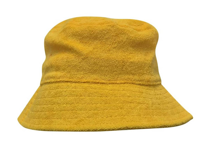 A yellow terry towelling bucket hat with a soft texture and a wide brim. It features a logo.