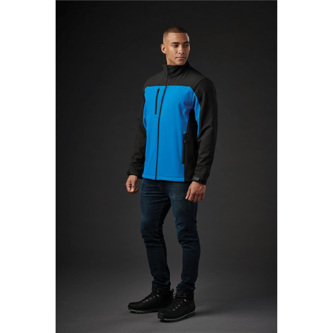 A softshell jacket in blue and black worn by a model, featuring a zipped front and a logo.