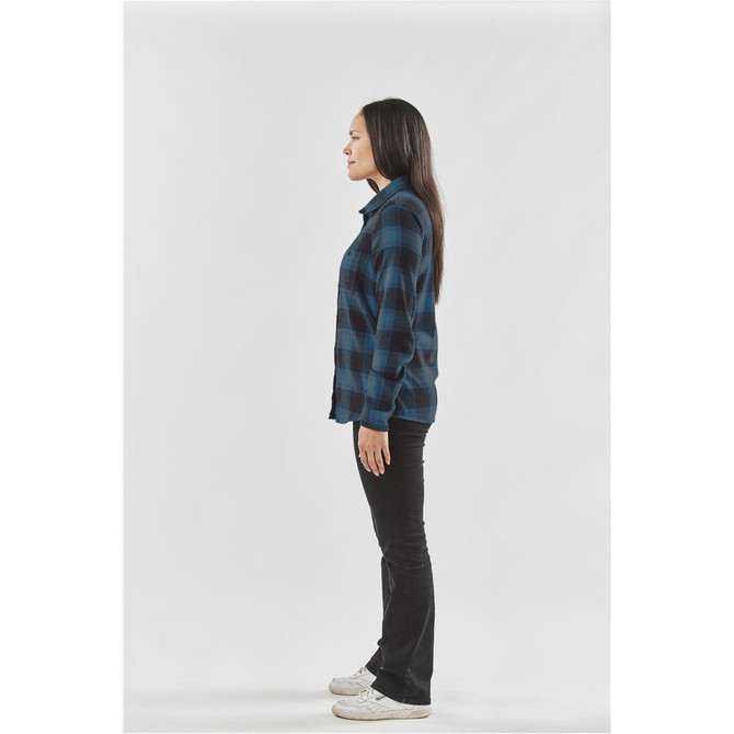 A side view of a woman wearing a blue and black checkered button-up shirt and black pants.