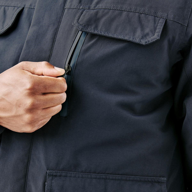 A close-up of a navy jacket featuring a zippered chest pocket and front flap pockets, held by a person's hand.
