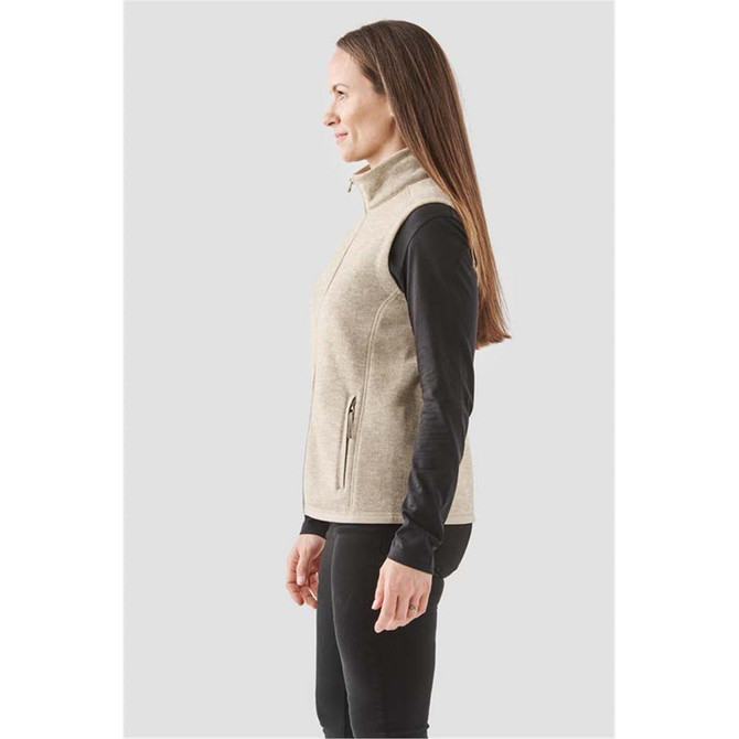A women's full zip fleece vest in a light beige shade, featuring a zippered pocket and a logo.