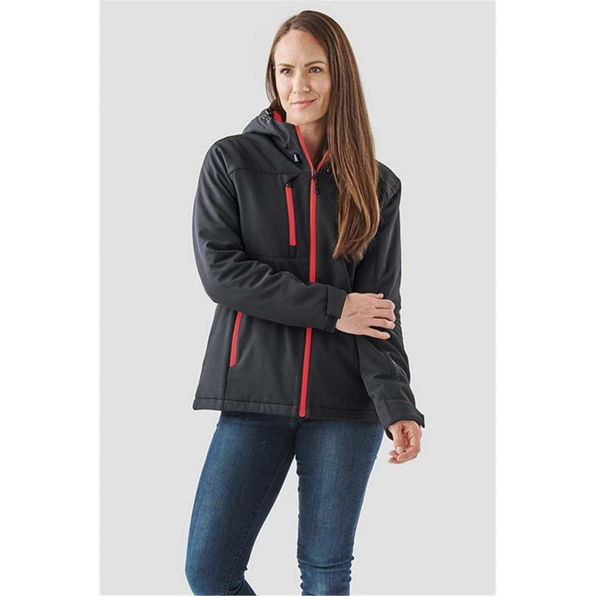 A woman wearing a black insulated softshell jacket with red accents and a hood, standing against a neutral background.