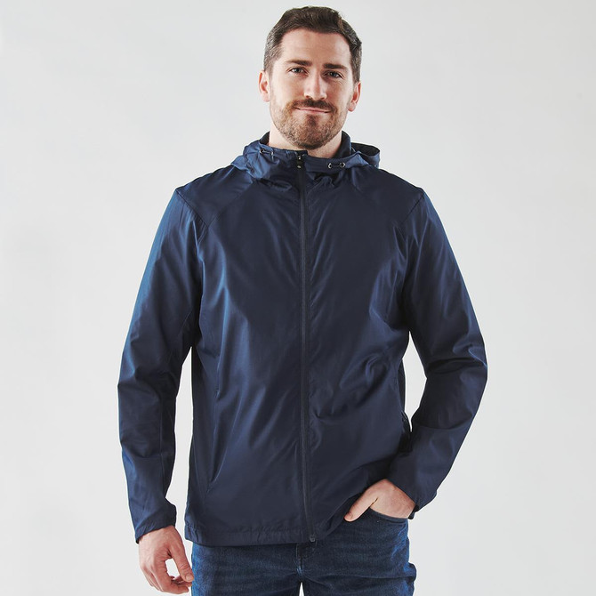 A navy wind jacket features a hood, front zip, and a logo on the chest, worn by a smiling man.