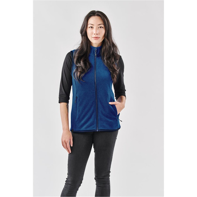 A woman wearing a navy blue vest with a front zip and side pockets, paired with a black top and jeans.