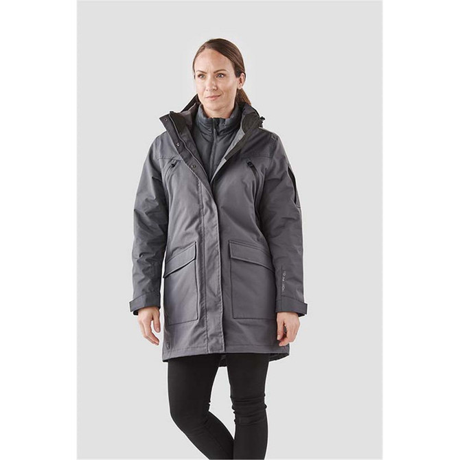 A woman in a grey 5-in-1 system jacket featuring multiple pockets and a hood, standing against a light background.