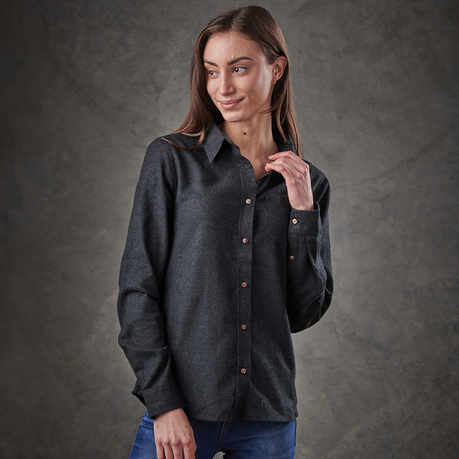 A woman models a long-sleeve, button-up shirt in dark grey, featuring a front pocket and a subtle logo.
