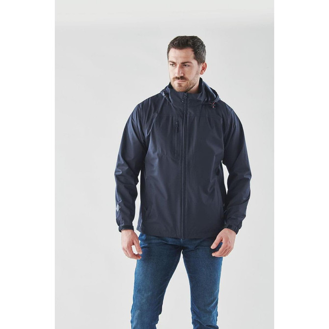 A man is wearing a navy lightweight rain jacket, featuring a hood and a logo on the chest.