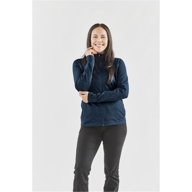 A woman wearing a navy blue performance jacket, standing with a slight smile against a neutral background.