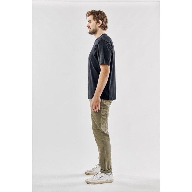 A black men's t-shirt displayed from the side, paired with khaki pants and white sneakers. The shirt features a logo.