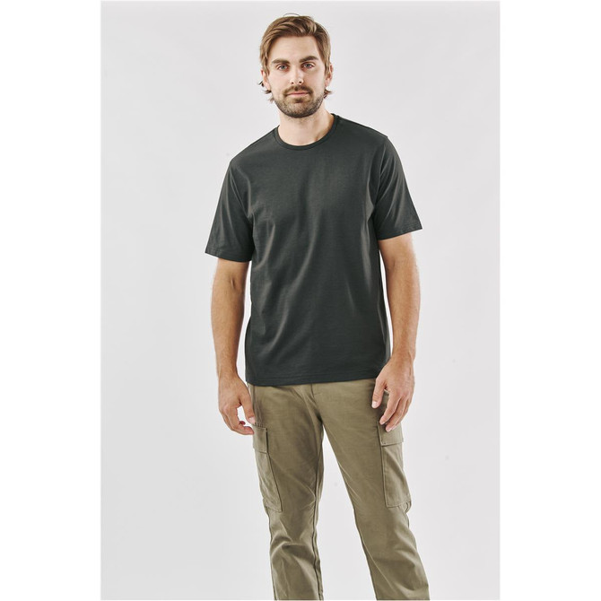 A man wearing a dark green short-sleeve T-shirt, paired with khaki cargo pants, standing against a neutral background.