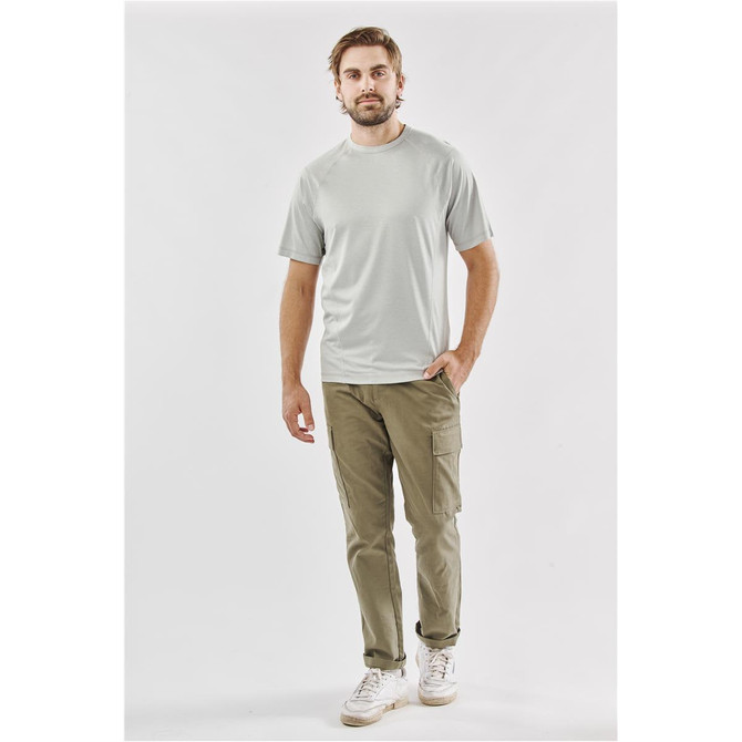 A man in a light grey T-shirt paired with khaki cargo pants, standing against a neutral background. The shirt has a logo.