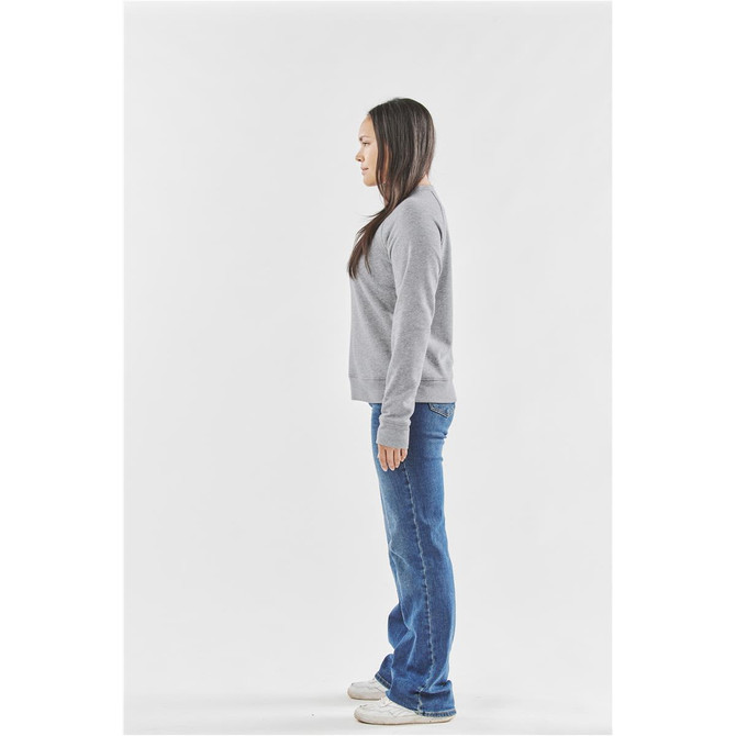 A side view of a woman wearing a grey women's Monashee Henley shirt paired with blue jeans. The shirt has a logo.