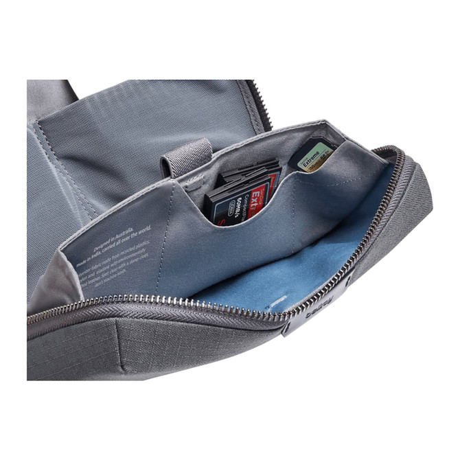 A grey tech kit with multiple compartments, featuring slots for memory cards and a soft blue lining.