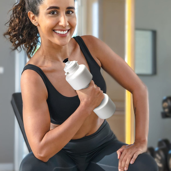 A drink bottle designed like a dumbbell, featuring a white colour, held by a smiling woman in activewear.