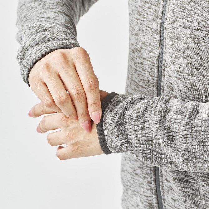 A close-up of a woman's hands adjusting the cuffs of a grey fleece jacket with a full zip.