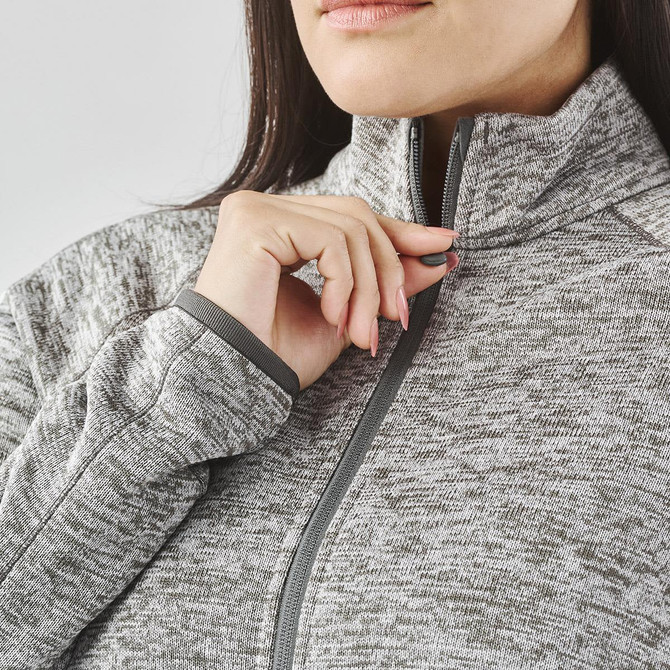 A close-up of a woman's neck and shoulder wearing a grey full zip fleece jacket with a high collar.