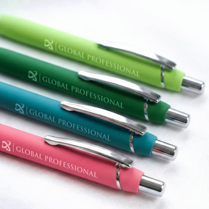 A set of four soft-touch pens in green, teal, dark green, and pink, each with a silver clip and branding.