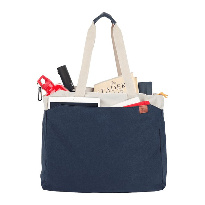 A navy tote bag filled with a drink bottle, tablet, book, and various other items, featuring handles and a logo.