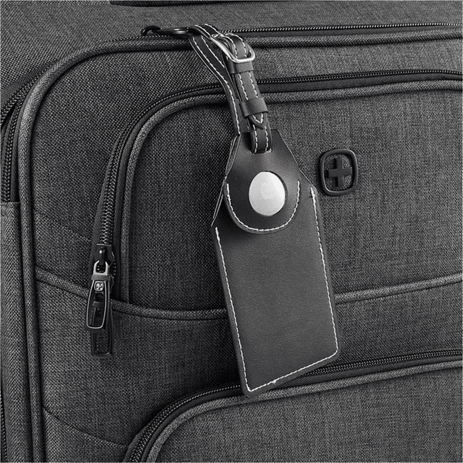 A black luggage tag with an AirTag holder attached to a grey suitcase, featuring a logo on the suitcase.