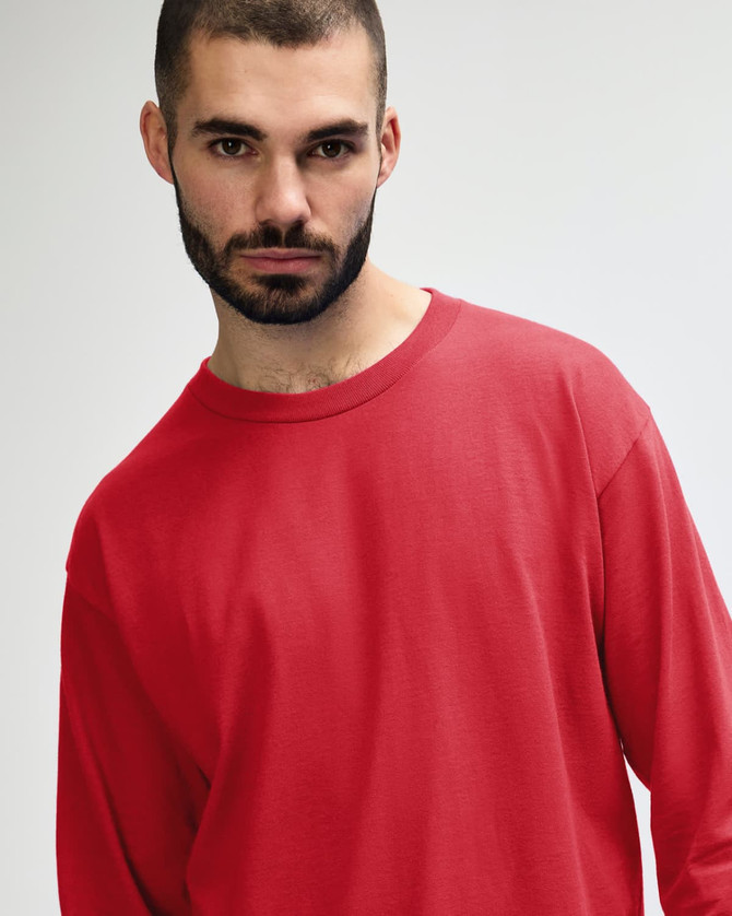 A red long sleeve t-shirt with a relaxed fit, featuring a logo on the front.