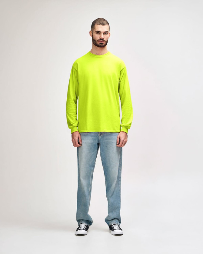 A model wearing a bright yellow long sleeve T-shirt paired with black jeans and sneakers, featuring a logo.