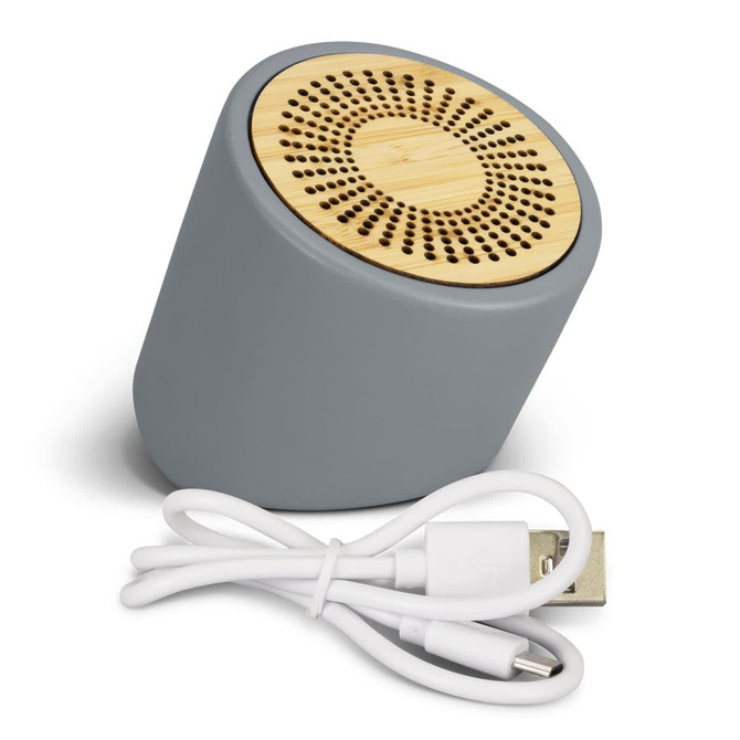A grey Bluetooth mini speaker with a bamboo grill, accompanied by a charging cable.