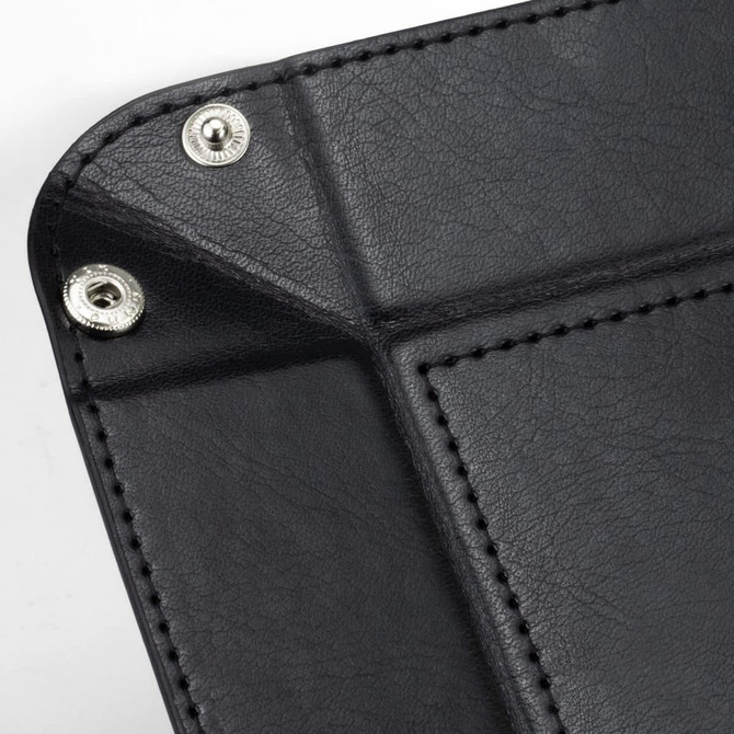 A black valet tray featuring silver snap fasteners and textured detailing on the surface.