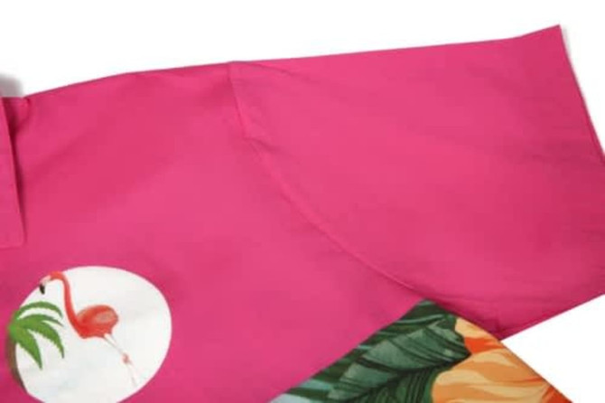 A vibrant pink sports jersey featuring a flamingo graphic and tropical foliage design. It has a logo on the fabric.