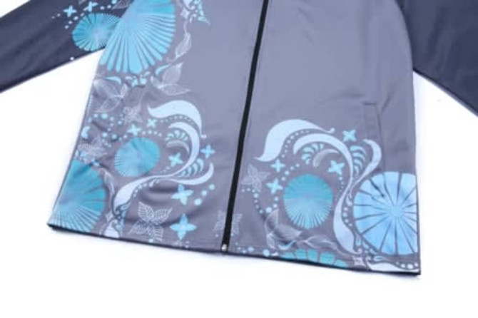 A grey school wear jacket featuring blue patterned designs and a zip closure. It includes a logo.